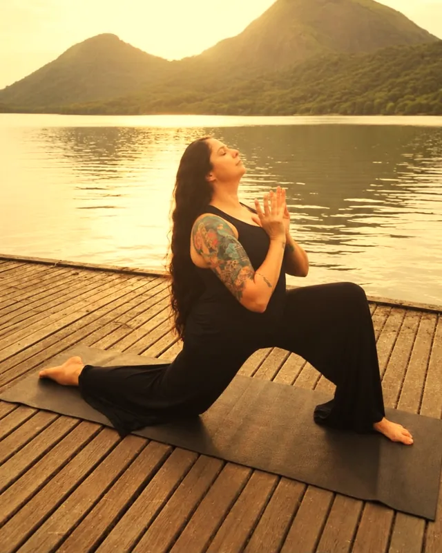 Alice Pedra em postura de yoga num deck à beira de um lago